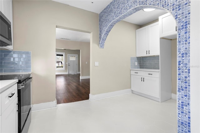 kitchen featuring white cabinetry, light tile patterned floors, decorative backsplash, and electric stove