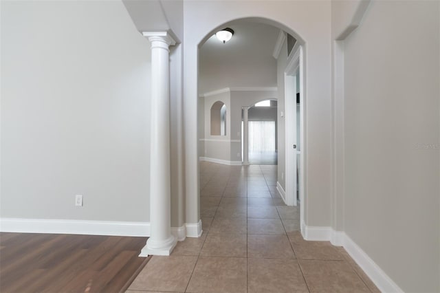 hallway featuring ornate columns, crown molding, and light tile patterned floors