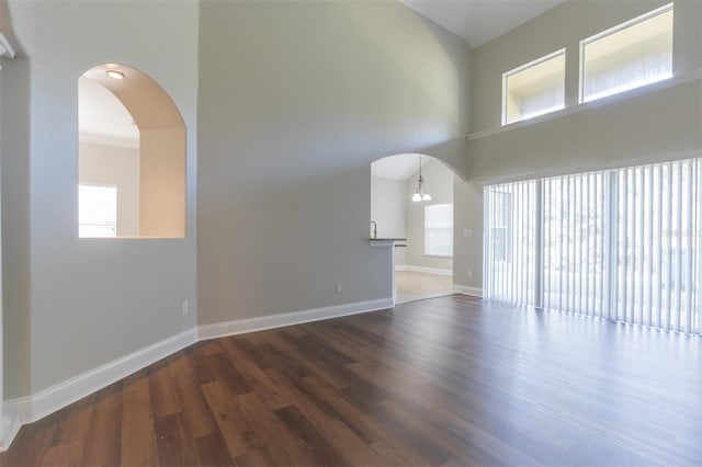 unfurnished living room with a high ceiling and dark wood-type flooring