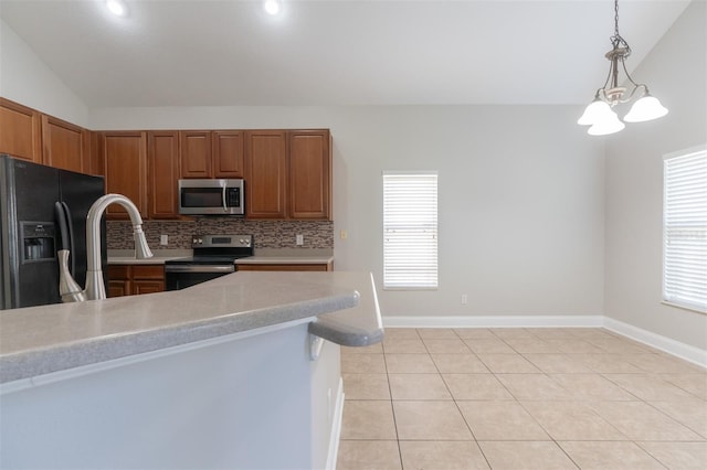 kitchen featuring lofted ceiling, hanging light fixtures, light tile patterned floors, stainless steel appliances, and decorative backsplash