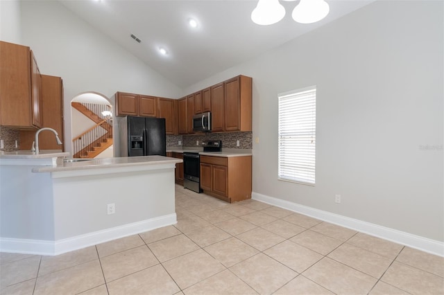 kitchen featuring light tile patterned flooring, appliances with stainless steel finishes, backsplash, and an inviting chandelier