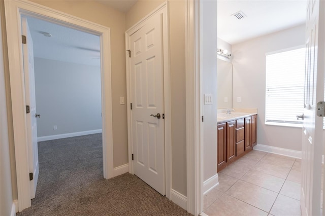 hall featuring sink and light tile patterned floors