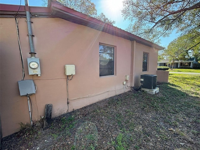 view of side of property with central AC and a lawn