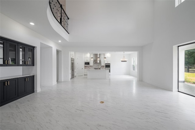 unfurnished living room featuring a notable chandelier and a high ceiling