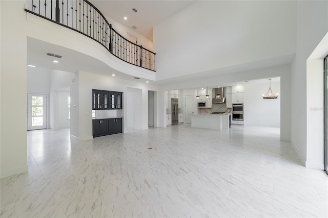 unfurnished living room featuring a notable chandelier and a towering ceiling