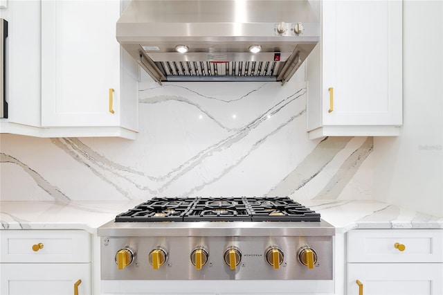 kitchen featuring light stone counters, white cabinets, island range hood, and stainless steel gas stovetop