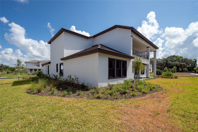 view of side of home featuring a balcony and a lawn