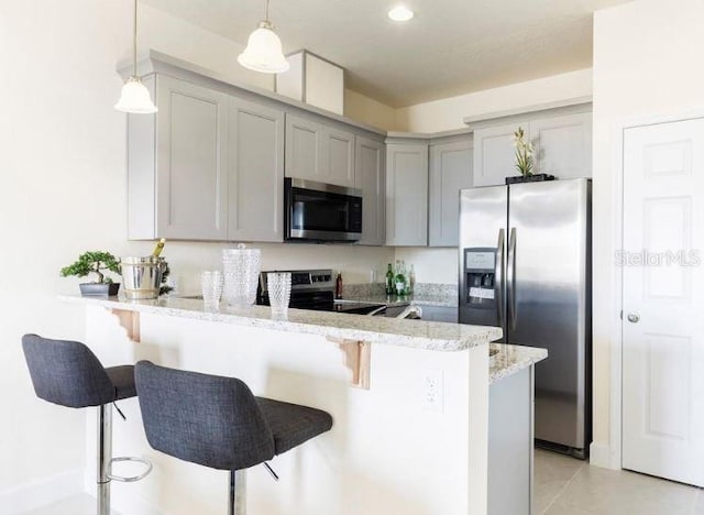 kitchen with a kitchen bar, gray cabinetry, appliances with stainless steel finishes, kitchen peninsula, and pendant lighting