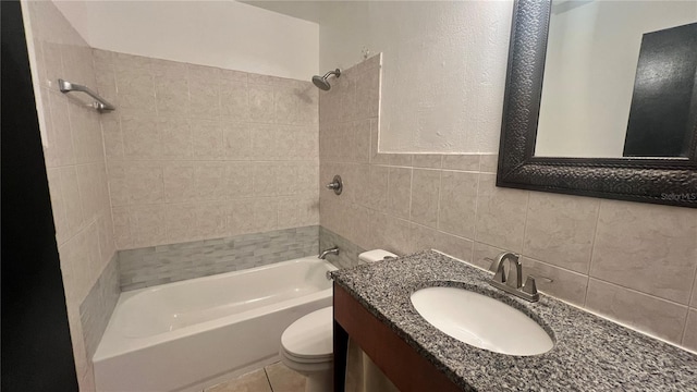 full bathroom with tile walls, tiled shower / bath combo, vanity, toilet, and tile patterned floors