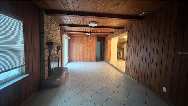 unfurnished living room with light tile patterned flooring, a fireplace, wood walls, wooden ceiling, and beam ceiling