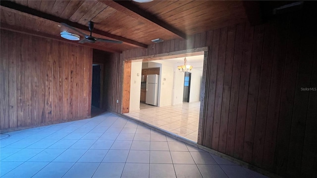 unfurnished room with wooden walls, beam ceiling, ceiling fan with notable chandelier, and wooden ceiling