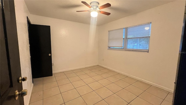 tiled spare room featuring ceiling fan