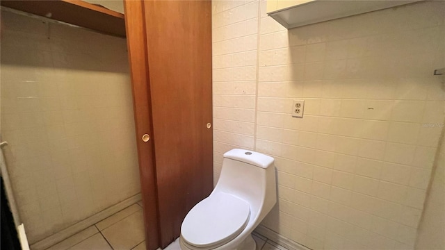 bathroom featuring toilet, tile patterned flooring, and tile walls