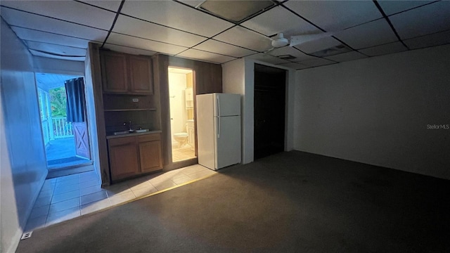 interior space featuring light tile patterned flooring, a paneled ceiling, and white fridge