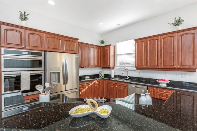 kitchen with stainless steel appliances, sink, and dark stone counters