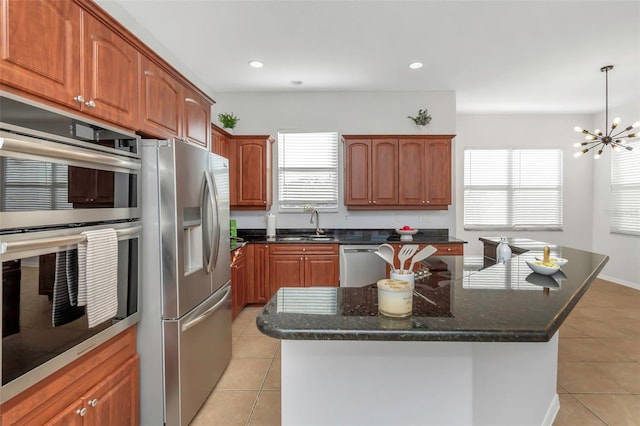 kitchen featuring hanging light fixtures, stainless steel appliances, a center island, a wealth of natural light, and light tile patterned flooring