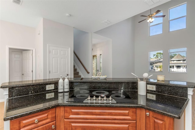 kitchen featuring black cooktop, ceiling fan, and dark stone counters