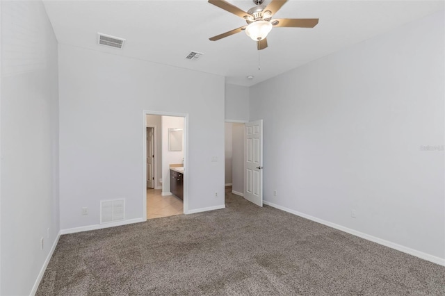 unfurnished bedroom featuring ceiling fan, light colored carpet, and connected bathroom