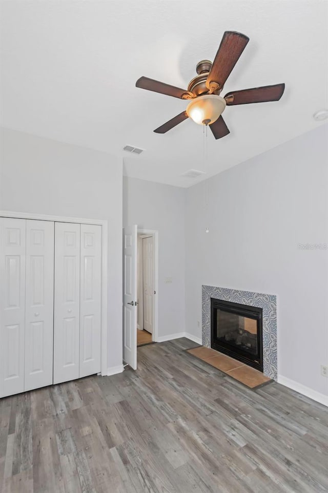 unfurnished living room with a tile fireplace, ceiling fan, and light hardwood / wood-style floors