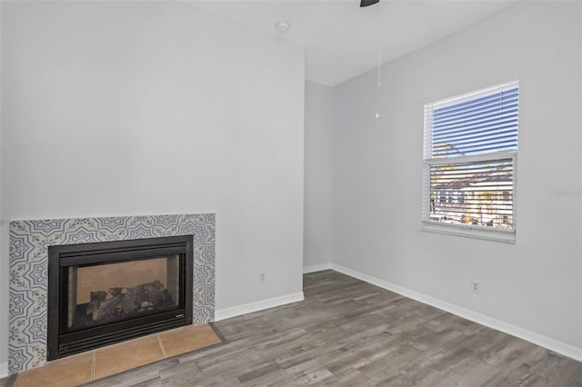 unfurnished living room featuring ceiling fan, wood-type flooring, and a fireplace