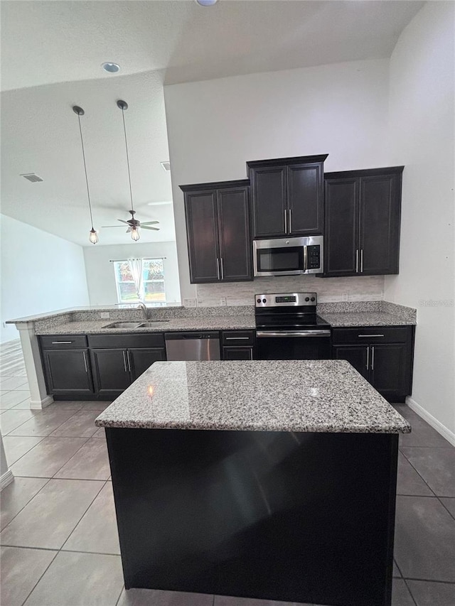 kitchen featuring light tile patterned flooring, sink, a center island, hanging light fixtures, and appliances with stainless steel finishes