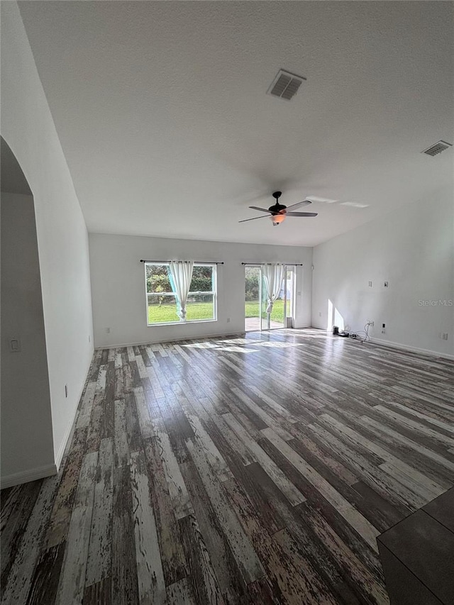 unfurnished living room with ceiling fan, dark wood-type flooring, and a textured ceiling