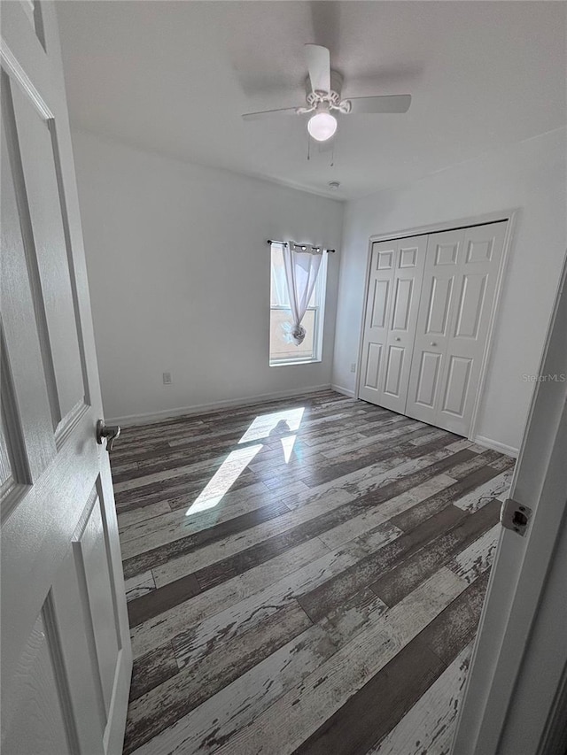 unfurnished bedroom with dark wood-type flooring, ceiling fan, and a closet