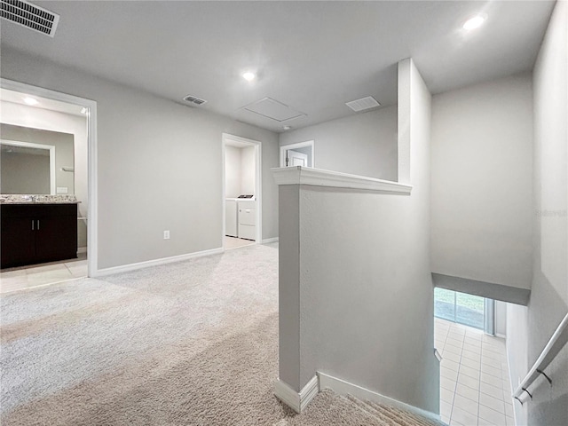 corridor with light carpet and washer and clothes dryer