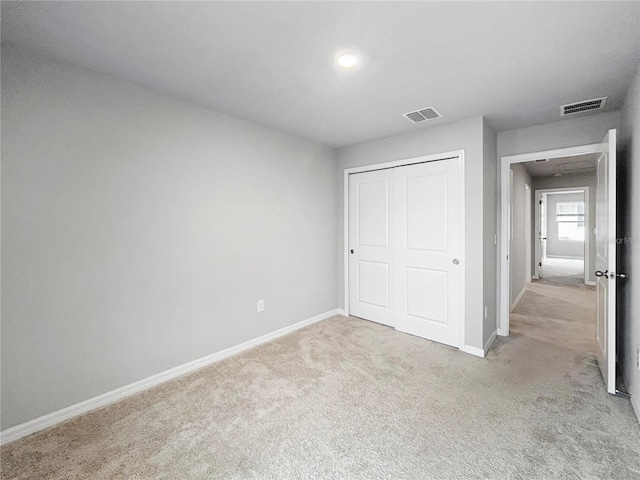 unfurnished bedroom featuring light colored carpet and a closet