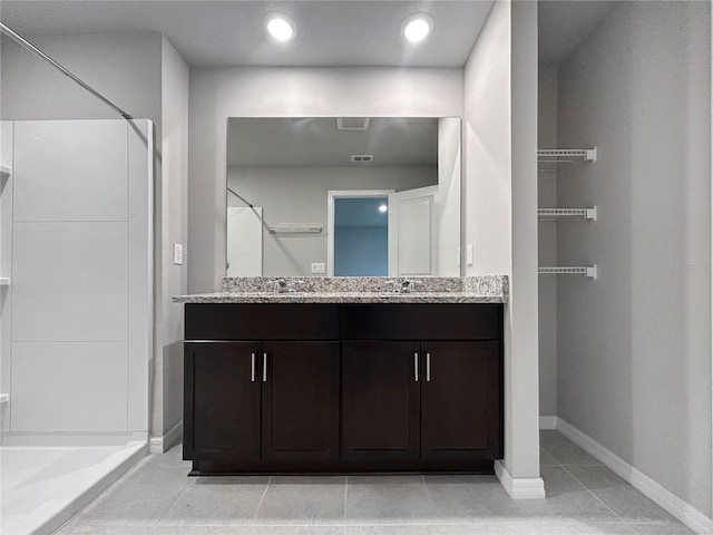 bathroom with tile patterned flooring, vanity, and walk in shower