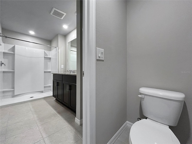 bathroom featuring vanity, tile patterned flooring, toilet, and walk in shower