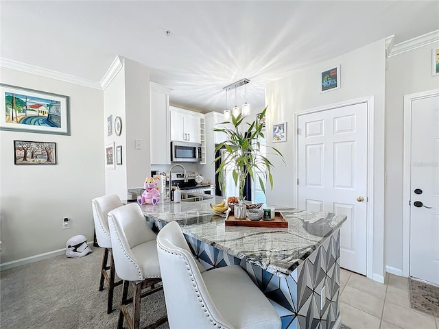 dining space with sink, light tile patterned floors, and ornamental molding