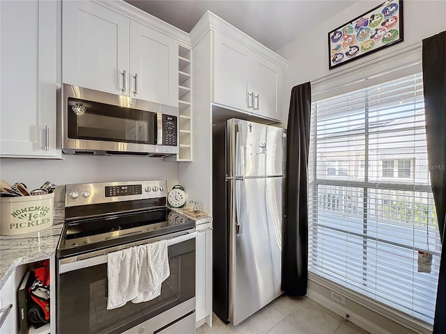 kitchen with white cabinetry, light tile patterned floors, light stone countertops, and appliances with stainless steel finishes