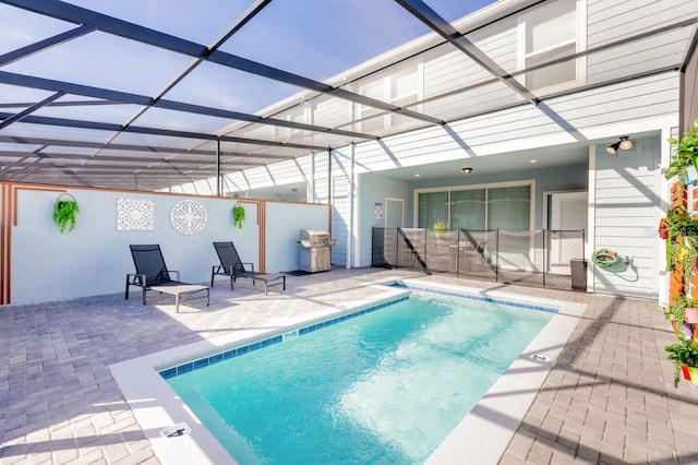 view of pool with grilling area, a patio, and glass enclosure