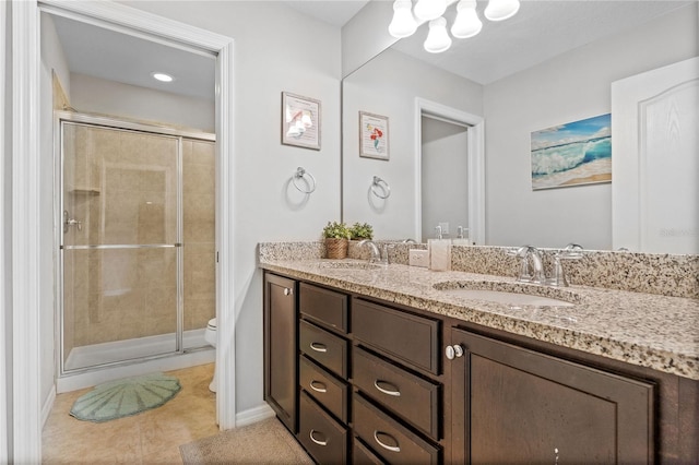 bathroom with a shower with door, vanity, tile patterned flooring, and toilet