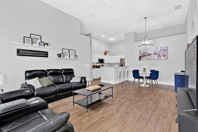 living room with an inviting chandelier and light hardwood / wood-style flooring