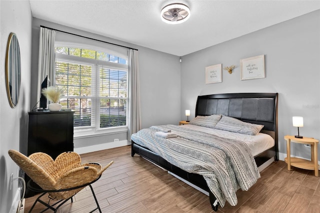 bedroom with a textured ceiling, stainless steel fridge, and wood-type flooring