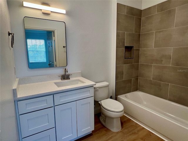 full bathroom with wood-type flooring, toilet, tiled shower / bath combo, and vanity