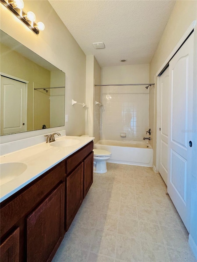 full bathroom featuring vanity, tiled shower / bath combo, a textured ceiling, and toilet