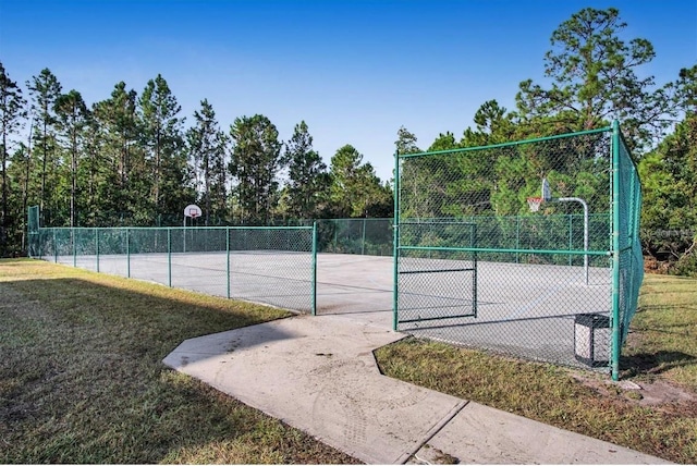 view of tennis court featuring a yard and basketball hoop