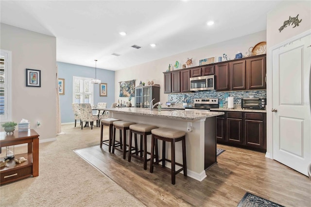 kitchen with pendant lighting, sink, a breakfast bar, appliances with stainless steel finishes, and a kitchen island with sink