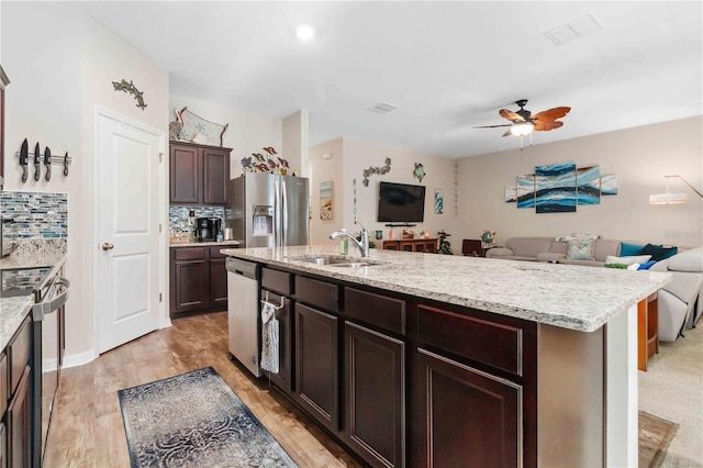 kitchen with stainless steel appliances, sink, a center island with sink, and decorative backsplash