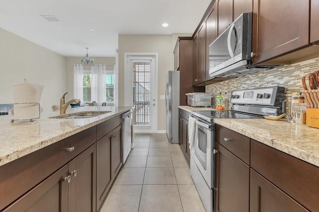 kitchen featuring sink, decorative light fixtures, stainless steel appliances, and light stone countertops