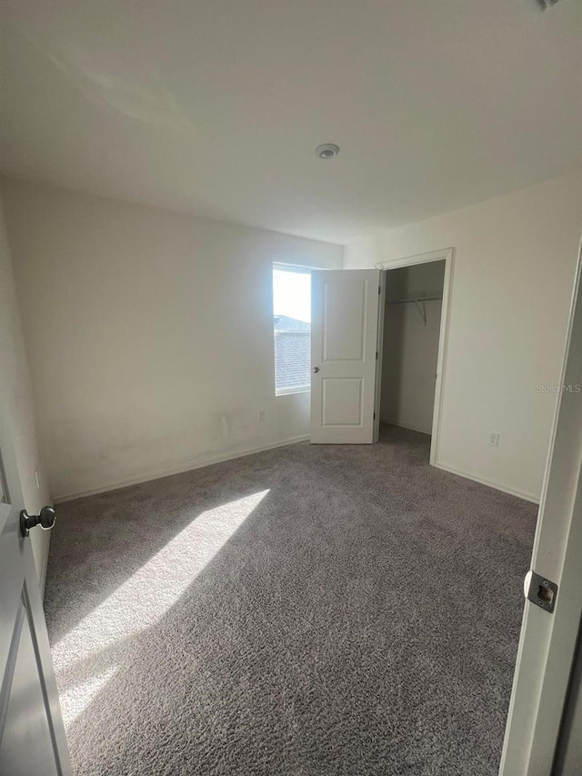 unfurnished bedroom featuring dark carpet and a closet