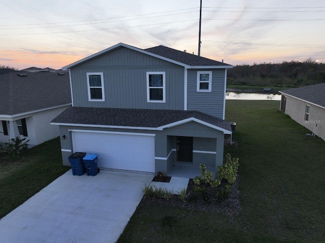 front of property featuring a garage, a water view, and a lawn