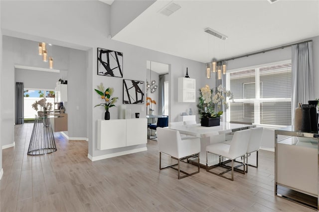 dining area with a chandelier, a high ceiling, and light wood-type flooring