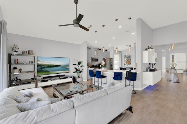 living room featuring vaulted ceiling, ceiling fan, and light hardwood / wood-style floors