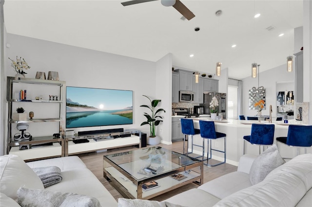 living room featuring lofted ceiling, light hardwood / wood-style floors, and ceiling fan