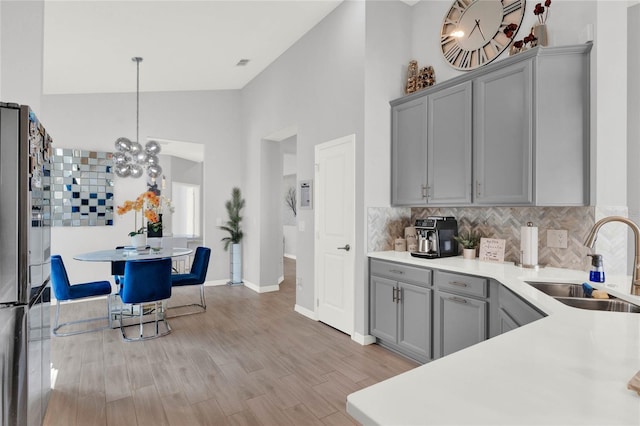 kitchen featuring pendant lighting, sink, stainless steel fridge, gray cabinets, and decorative backsplash