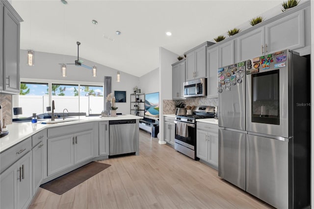 kitchen featuring lofted ceiling, sink, gray cabinetry, backsplash, and stainless steel appliances